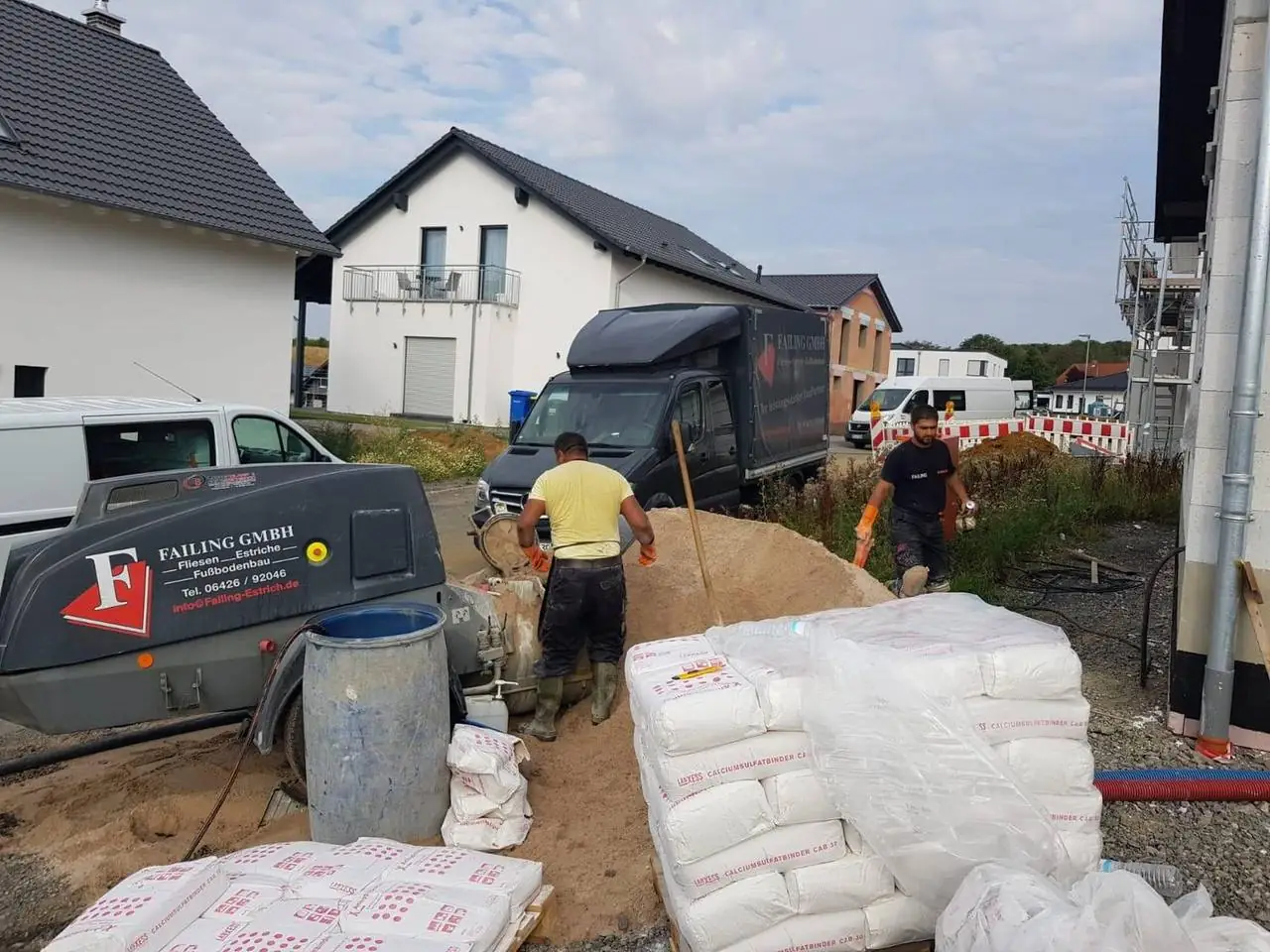 Estrichpumpe, Materialsäcke und Mitarbeiter in einem Neubaugebiet