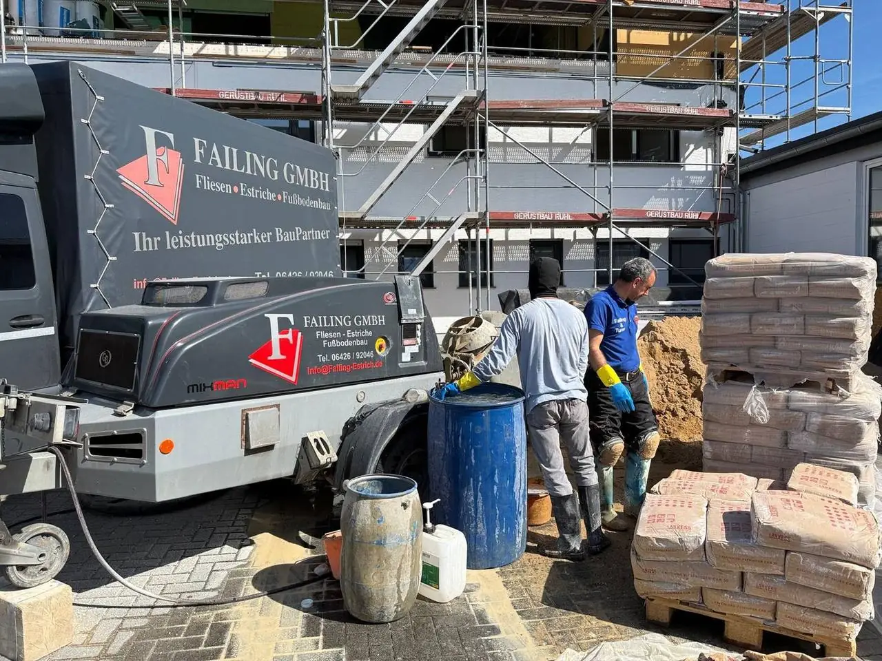 Zwei Mitarbeiter der Failing GmbH arbeiten gemeinsam an der Estrichpumpe auf einer Baustelle