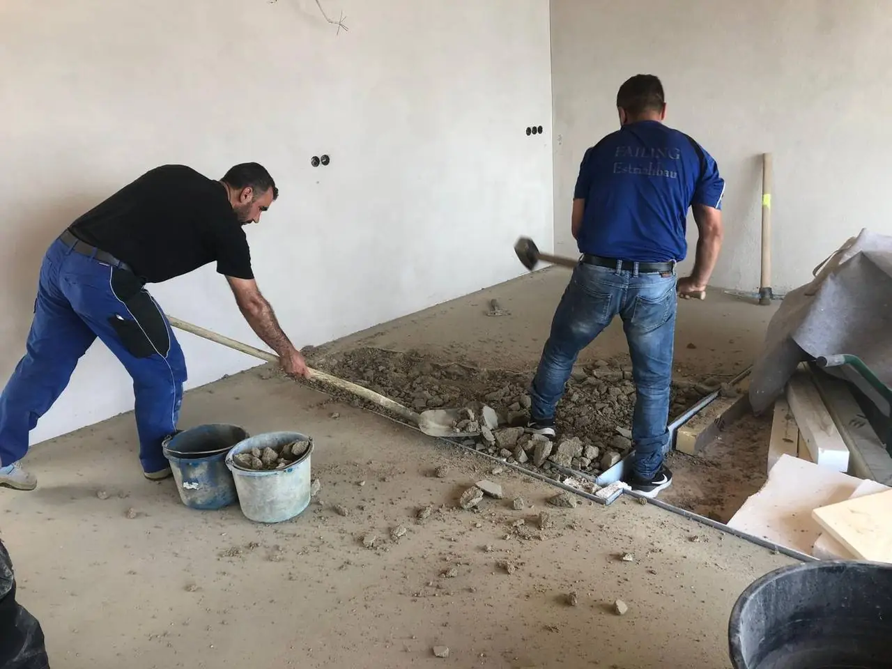 Zwei Mitarbeiter bauen alten Estrich für eine Sanierung aus