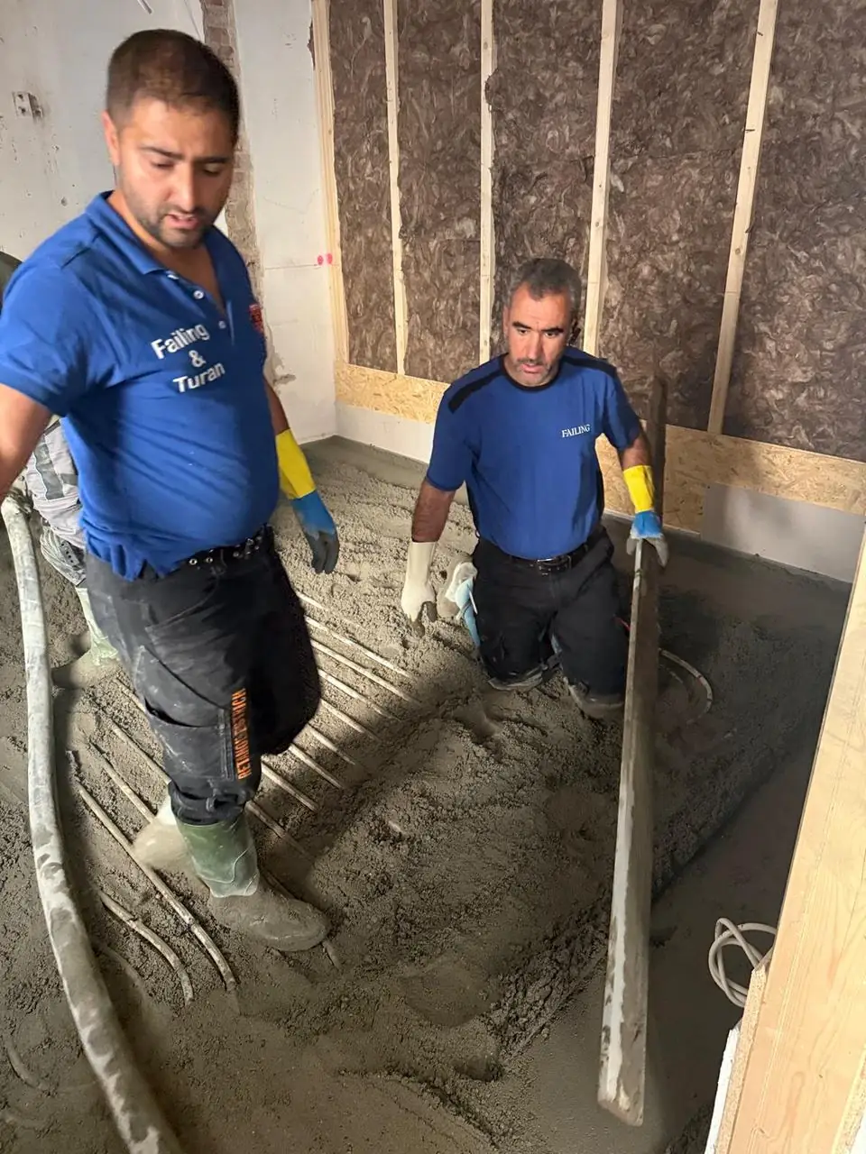 Zwei Mitarbeiter beim Estricheinbau im Innenraum